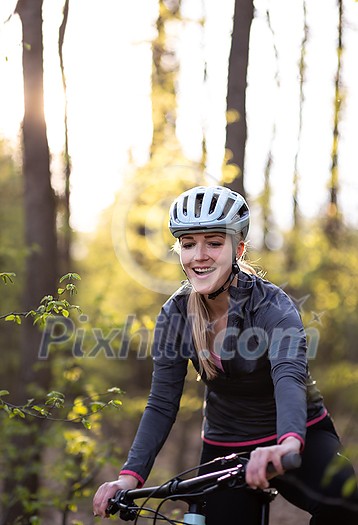 Pretty, young woman with her mountain bike going for a ride past the city limits, getting her dose of daily cardio