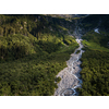 Aerial top view of summer green trees in forest with a splendid mountain river in Swiss Alps