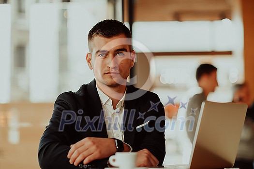 Happy businessman sitting at the cafeteria with laptop and smartphone. Businessman texting on smartphone while sitting in a pub restaurant. Businessman working and checking email on the computer. Happy businessman sitting at the cafeteria with laptop and smartphone. Businessman texting on smartphone while sitting in a pub restaurant. Businessman working and checking email on the computer.