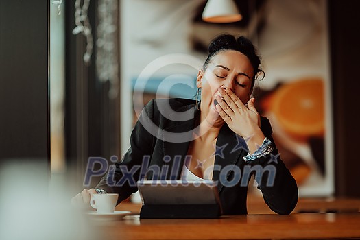 a sleepy woman sits in a cafe during a break and uses a tablet