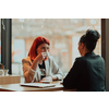 One-on-one meeting.Two young business women sitting at table in cafe.Girl using laptop, smartphone, blogging. Teamwork, business meeting. Freelancers working.