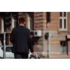 Portrait of a tourist man carrying a suitcase and holding a cup of coffee while walking outdoors on the street. Tourism concept.