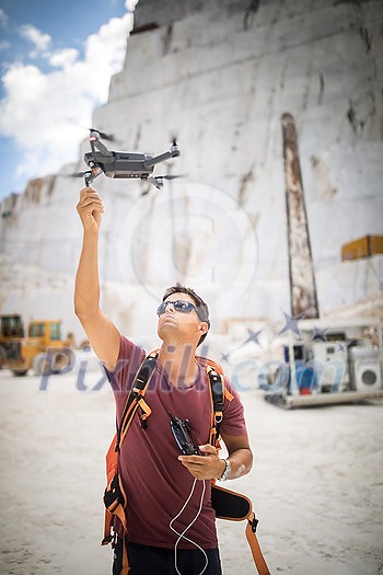 Young man flying his drone , rtaking aerial photos of a site Young man flying his drone , rtaking aerial photos of a site