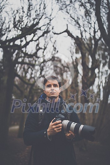 Young man devoting time to his favorite hobby - photography - taking photos outdoor with his digital camera/DSLR Young man devoting time to his favorite hobby - photography - taking photos outdoor with his digital camera/DSLR