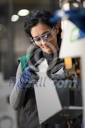 Woman worker wearing safety goggles control lathe machines to drill components. Metal lathe industrial manufacturing factory. High quality photo Woman worker wearing safety goggles control lathe machines to drill components. Metal lathe industrial manufacturing factory. High quality photo