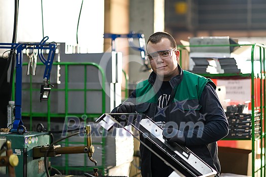 a uniformed worker working in a modern metal production and processing factory assembles parts of a new machine on his desk. High quality photo a uniformed worker working in a modern metal production and processing factory assembles parts of a new machine on his desk. High quality photo