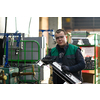 a uniformed worker working in a modern metal production and processing factory assembles parts of a new machine on his desk. High quality photo