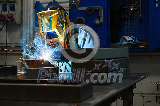 Professional welder performs work with metal parts in factory, sparks and electricity. Industry worker banner. High quality photo