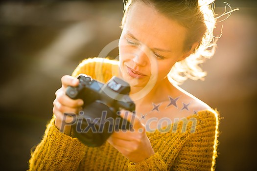 Hobby photographer concept. Outdoor lifestyle portrait of young woman taking photos with her mirrorless camera in warm evening sunlight Hobby photographer concept. Outdoor lifestyle portrait of young woman taking photos with her mirrorless camera in warm evening sunlight