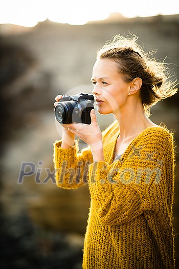 Hobby photographer concept. Outdoor lifestyle portrait of young woman taking photos with her mirrorless camera in warm evening sunlight Hobby photographer concept. Outdoor lifestyle portrait of young woman taking photos with her mirrorless camera in warm evening sunlight