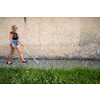 Blind woman walking on city streets, using her white cane to navigate the urban space better and to get to her destination safely