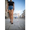 Blind woman walking on city streets, using her white cane to navigate the urban space better and to get to her destination safely