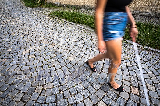 Blind woman walking on city streets, using her white cane to navigate the urban space better and to get to her destination safely Blind woman walking on city streets, using her white cane to navigate the urban space better and to get to her destination safely