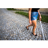 Blind woman walking on city streets, using her white cane to navigate the urban space better and to get to her destination safely