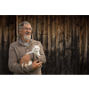 An elderly man holds a cute white kitten and smiles to the camera, selective focus, plenty of copy space