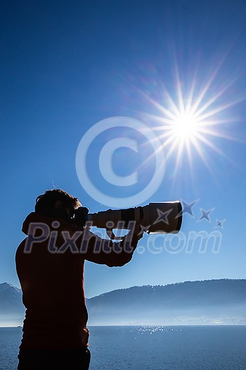 Senior man devoting time to his favorite hobby - photography - taking photos outdoor with his digital camera/DSLR and a big telephoto lens Senior man devoting time to his favorite hobby - photography - taking photos outdoor with his digital camera/DSLR and a big telephoto lens