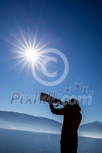 Young man devoting time to his favorite hobby - photography - taking photos outdoor with his digital camera/DSLR and a big telephoto lens Young man devoting time to his favorite hobby - photography - taking photos outdoor with his digital camera/DSLR and a big telephoto lens