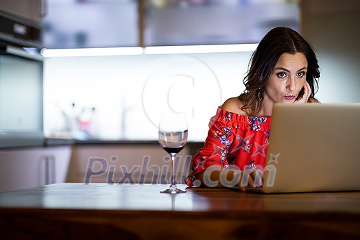 Pretty, mid-aged woman having a virtual Wine Tasting Dinner Event Online Using Laptop with friends