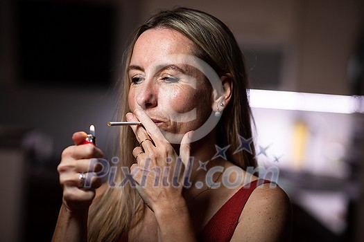 Mid-aged woman lighting a cigarette at home, getting her nicotine daily dose Mid-aged woman lighting a cigarette at home, getting her nicotine daily dose