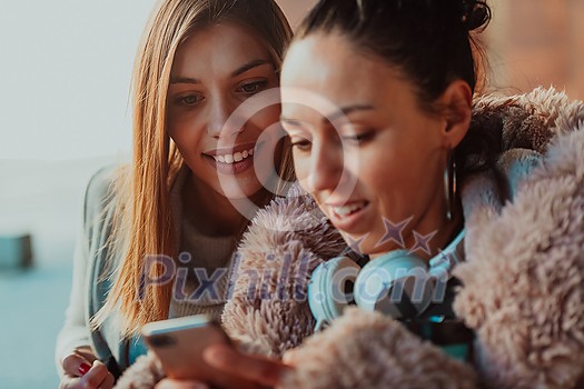 two friends stand in front of the university and use a smartphone for fun two friends stand in front of the university and use a smartphone for fun