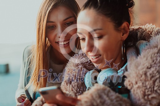 two friends stand in front of the university and use a smartphone for fun