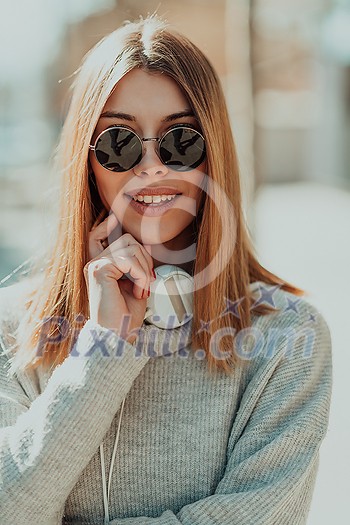a woman in sunglasses enjoys a walk in the city while listening to music on her headphones a woman in sunglasses enjoys a walk in the city while listening to music on her headphones