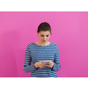 the girl uses a cell phone while standing in front of a pink background
