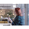 redhead business woman as influencer in creative modern coworking startup open space office using smart phone