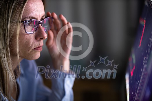 Stylish mid-aged woman looking concerned while remote working from home, staring at the computer screeen for long hours, exhausting her eyes with blue light