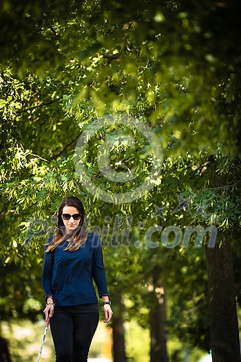 Blind woman walking on city streets, using her white cane to navigate the urban space better and to get to her destination safely Blind woman walking on city streets, using her white cane to navigate the urban space better and to get to her destination safely