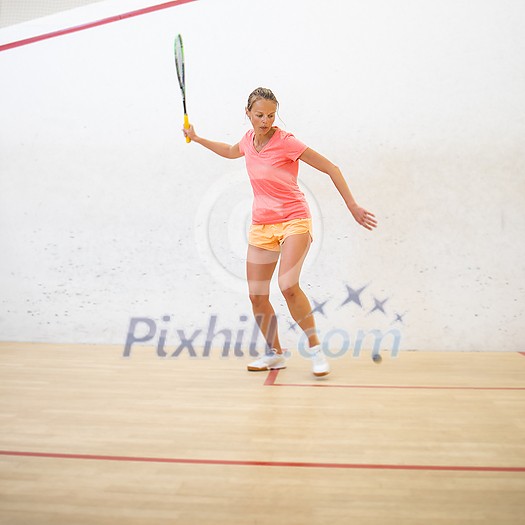 Pretty, female squash player on a squash court (motion blurred image; color toned image)