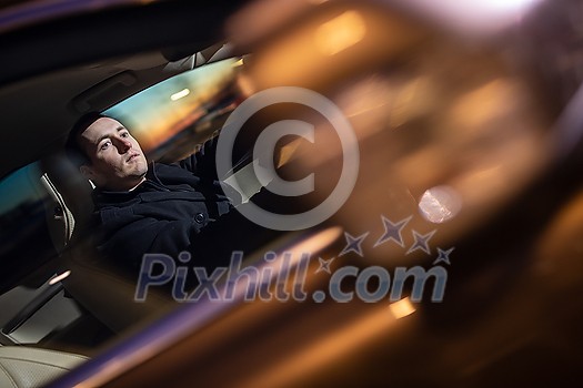 Handsome young man driving his car at night (color toned image; motion blurred image)