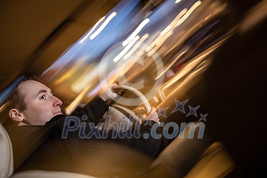 Handsome young man driving his car at night (color toned image; motion blurred image)