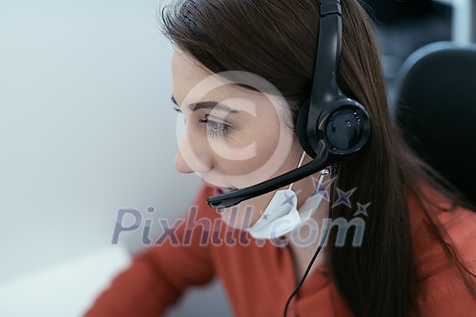 Female call center operator talking to a customer. Businesswoman in mask at the workplace in the modern office. Social distance and safety outbreak new normal concept Female call center operator talking to a customer. Businesswoman in mask at the workplace in the modern office. Social distance and safety outbreak new normal concept