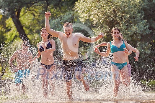 Summer joy group of happy friends having fun while running and splashing on river Summer joy group of happy friends having fun while running and splashing on river