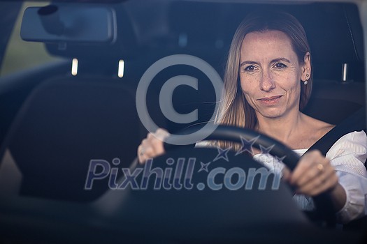 Pretty midle aged woman at the steering wheel of her car, going fast Pretty midle aged woman at the steering wheel of her car, going fast