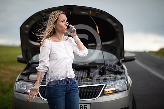 Pretty middle aged woman having car troubles - broken down car on the side of the road, calling the insurance company for assistance