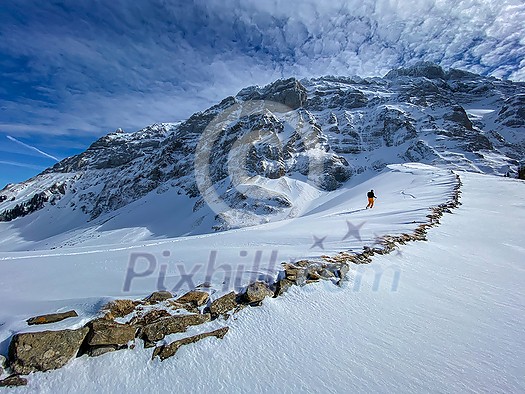 Winter sports - young man walking with snowshoes uphill in high mountains covered with lots of snow