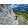 Pretty female climber on a steep Via Ferrata in the Swiss Alps - fearlessly climbing higher on this extreme alpine trail