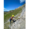 Pretty female climber on a steep Via Ferrata in the Swiss Alps - fearlessly climbing higher on this extreme alpine trail