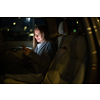 Young woman with her cell phone sitting in the backseat of a car, getting ready to travel (color toned image; shallow DOF)