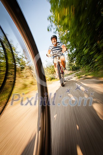 Senior man going fast on his bike during his regular afternoon ride - enjoying actively his retirement Senior man going fast on his bike during his regular afternoon ride - enjoying actively his retirement