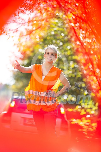 Young female driver wearing a high visibility vest, calling the roadside service/assistance after her car has broken down Young female driver wearing a high visibility vest, calling the roadside service/assistance after her car has broken down
