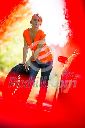 Young female driver wearing a high visibility vest, calling the roadside service/assistance after her car has broken down