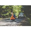 Pretty, young woman with her car broken down by the roadside, setting up the safety triangle, waiting for assistance