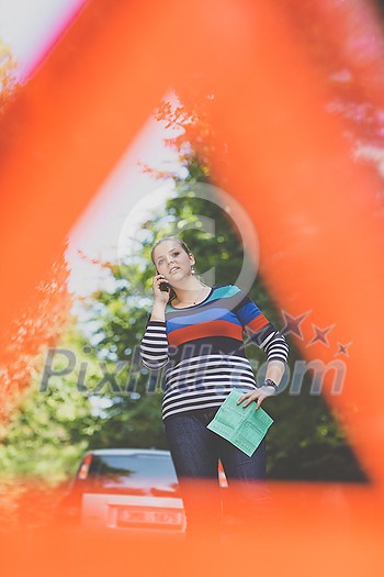 Pretty, young woman with her car broken down by the roadside, setting up the safety triangle, waiting for assistance Pretty, young woman with her car broken down by the roadside, setting up the safety triangle, waiting for assistance