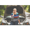 Pretty, young woman with her car broken down by the roadside, setting up the safety triangle, waiting for assistance