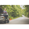 Pretty, young woman with her car broken down by the roadside, setting up the safety triangle, waiting for assistance