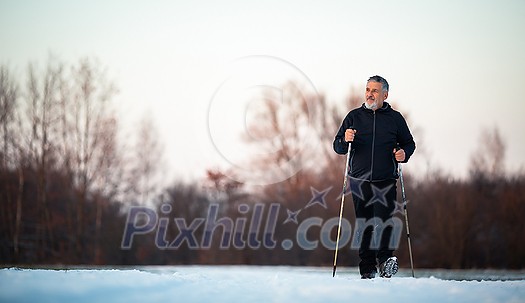 Senior man nordic walking outdoors on a snowy, winter day