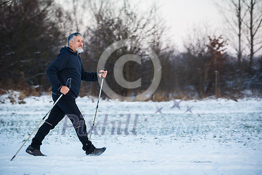 Senior man nordic walking outdoors on a snowy, winter day